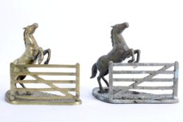 A pair of equestrian brass book ends cast as horses leaping a gate, on shaped rocky ground base,