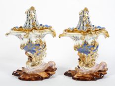 A pair of Jacob Petit blue ground cornucopia pot pourri vases with pierced covers, on rocky bases,