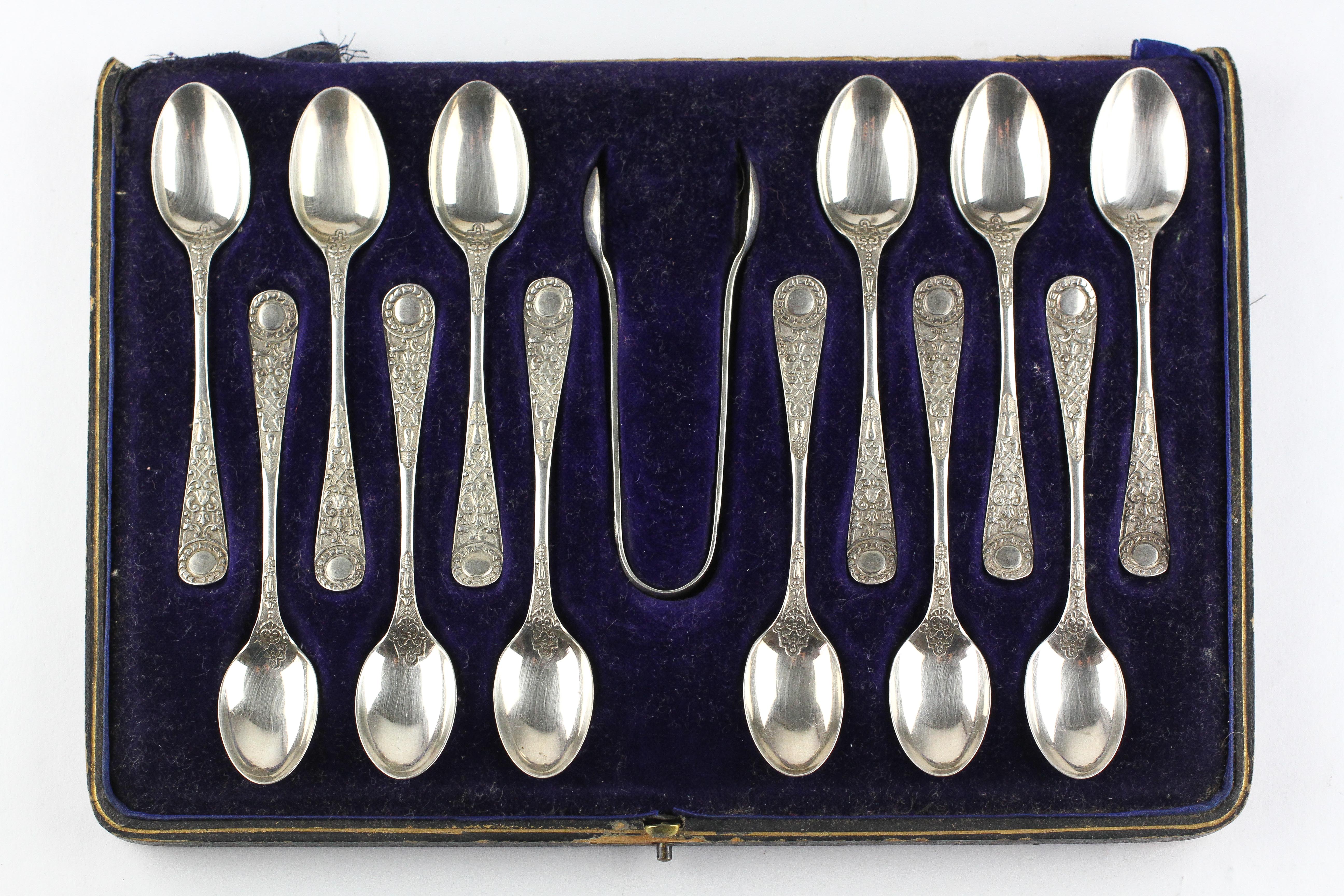 An early 20th century cased set of twelve silver teaspoons with matching sugar tongs,