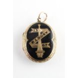 A yellow metal oval memorial picture locket with black enamel design.