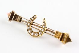 A yellow metal bar brooch having a central horseshoe set with graduated seed pearls.