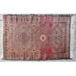 A Persian village rug, with three hooked medallions on an abrashed red ground,