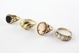 A collection of four rings to include an onyx signet ring, A cameo ring,