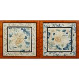 A pair of Chinese silk panels, circa 1900, worked with flowers inside a floral sprig border,