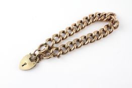 A yellow metal curb link bracelet with padlock and safety chain.