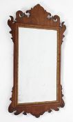 A George II style walnut wall mirror with foliate cresting, with cushion shaped parcel-gilt frame,