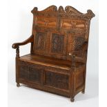 An oak hall bench, the scrolling toprail above carved panels with beasts and arched panels,