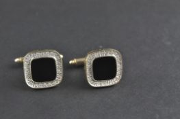 A yellow metal pair of cufflinks.