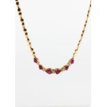 A yellow metal centrepiece necklace having heart shaped links and set with rubies and diamonds.