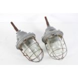A pair of vintage Russian industrial lamps, the glass dome inside a cage,