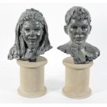 A pair of cast and painted metal busts of a boy and girl, initialled SJ'01,