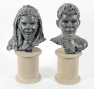 A pair of cast and painted metal busts of a boy and girl, initialled SJ'01,