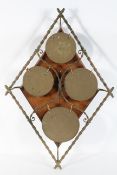 A wall mounted set of brass circular gongs, in a diamond bamboo effect frame, on an oak backboard,
