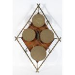 A wall mounted set of brass circular gongs, in a diamond bamboo effect frame, on an oak backboard,