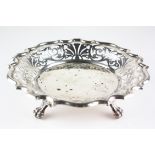 An Edwardian silver dish with pierced rim, raised upon three lion paw feet,