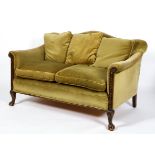 An Edwardian oak framed humpback two seater sofa, upholstered in green velvet,