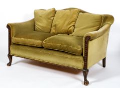 An Edwardian oak framed humpback two seater sofa, upholstered in green velvet,