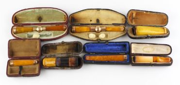 A collection of seven early 20th century amber pipes, including: four gold-mounted examples,