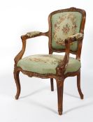 A French carved Louis XV style tapestry fauteuil, the toprail carved with flowers,