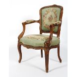 A French carved Louis XV style tapestry fauteuil, the toprail carved with flowers,