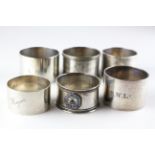 A assortment of six silver napkin rings of varying shapes and designs,