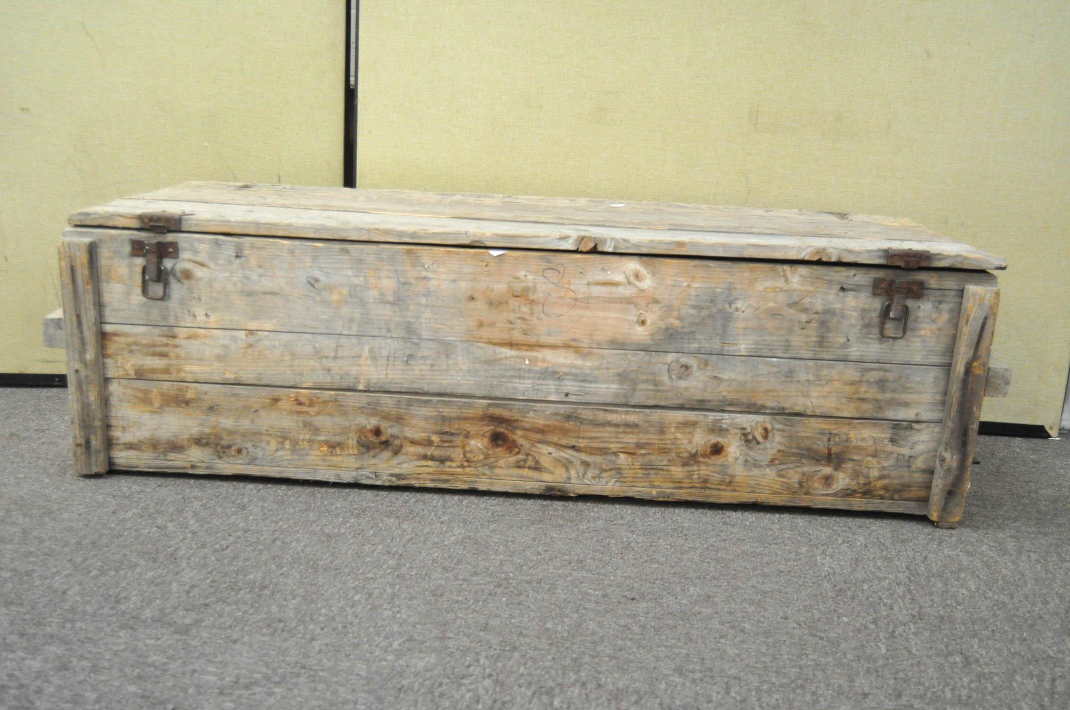 A large pine storage trunk, containing a selection of tools and petrol cans,