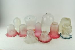 A collection of glass lamp shades, including shaded cranberry, vaseline and others,
