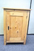 A vintage single door pine cupboard, opening to reveal two shelves,