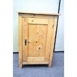 A vintage single door pine cupboard, opening to reveal two shelves,