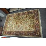 An Indian rug, with scrolling foliage on a beige ground,