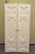 A white painted two door cupboard, enclosing three adjustable shelves,