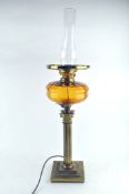 A brass oil lamp with an amber glass reservoir,