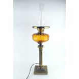 A brass oil lamp with an amber glass reservoir,