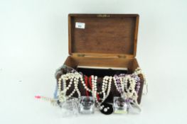 A wooden box containing a quantity of costume jewellery including earrings and necklaces