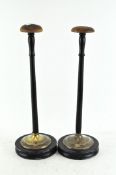 A pair of wig stands, with circular feet,