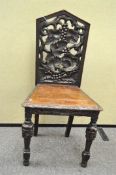 An oak hall chair, the back pierced with fruiting vines,