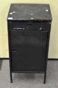A black painted metal storage cabinet, comprising single drawer over a single door cupboard,