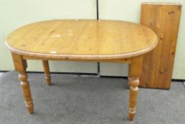 A modern oval pine extending dining table raised on turned legs,