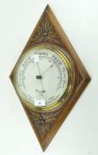 An oak aneroid barometer, early 20th century, in oak foliate-carved diamond-shaped case,