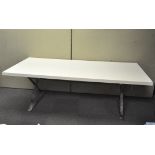 A large modern dining table of rectangular form, white top on chrome legs,