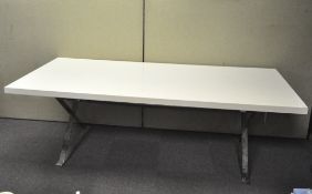 A large modern dining table of rectangular form, white top on chrome legs,