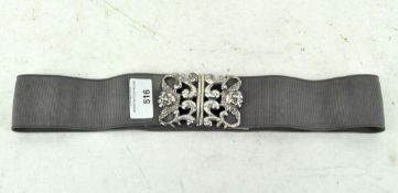 A modern Silver belt buckle attached to a fabric strap,