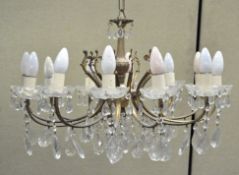 A twelve light gilt metal chandelier, with glass drip pans and glass droplets,
