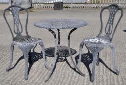 A grey aluminium table and two matching chairs, with pierced decoration, the table 65 cm high,