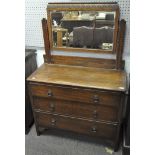 An Edwardian oak dressing table, with swing mirror above three long drawers,