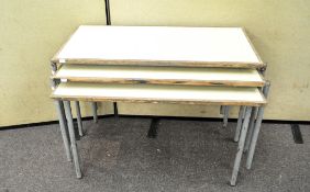 A set of three stacking school tables of rectangular form, each with four tubular metal legs,
