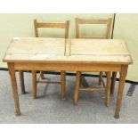 An early 20th century Oak child's two seat desk, each with lifting compartment,