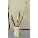 A ceramic stick stand containing various walking sticks,