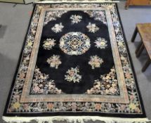A large Chinese black ground wool rug, decorated with traditional floral scenes,