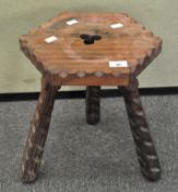 A carved wooden stool, raised on three splayed legs,